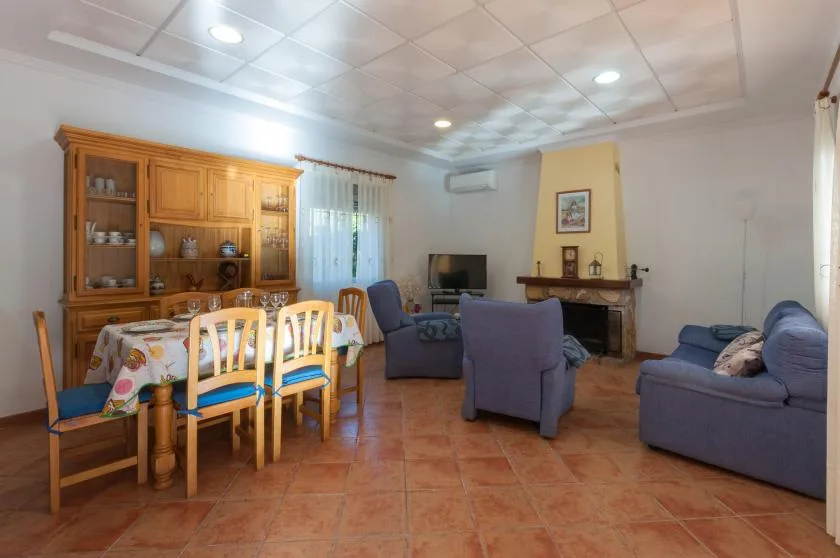 A living and dining room with a table, seating, and a television.