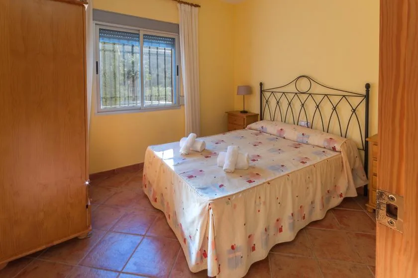 A bedroom with a double bed, patterned bedding, and a window.