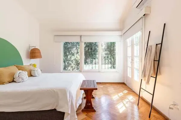 Un dormitorio luminoso con una cama y grandes ventanas con vista a la vegetación.