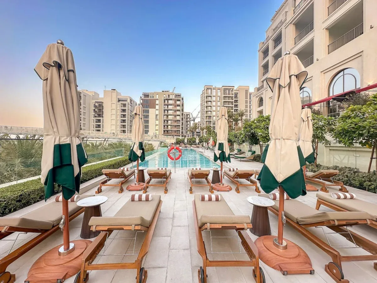 Una terraza junto a la piscina con tumbonas y sombrillas cerradas.