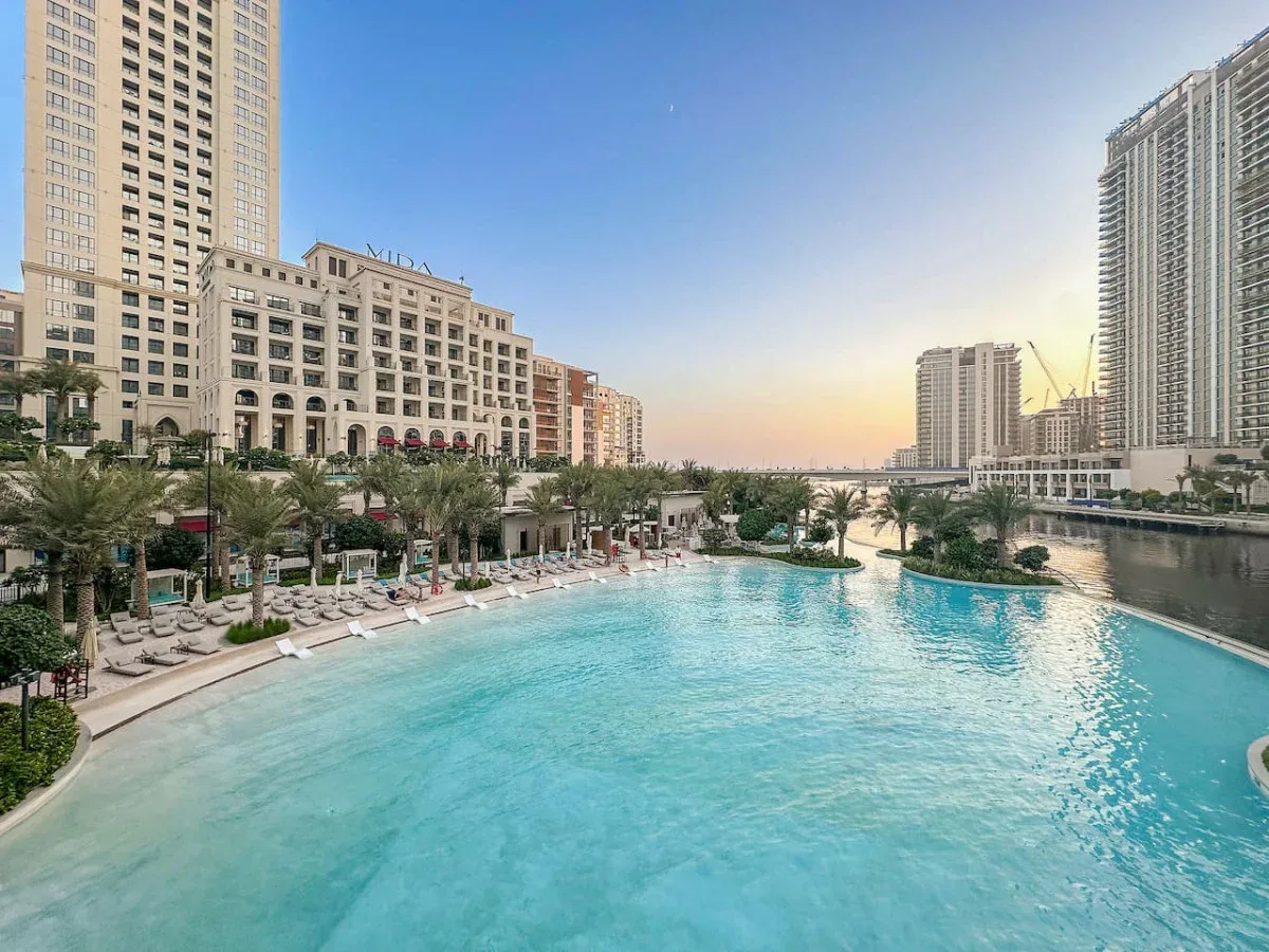 Una piscina está rodeada de palmeras y edificios altos.