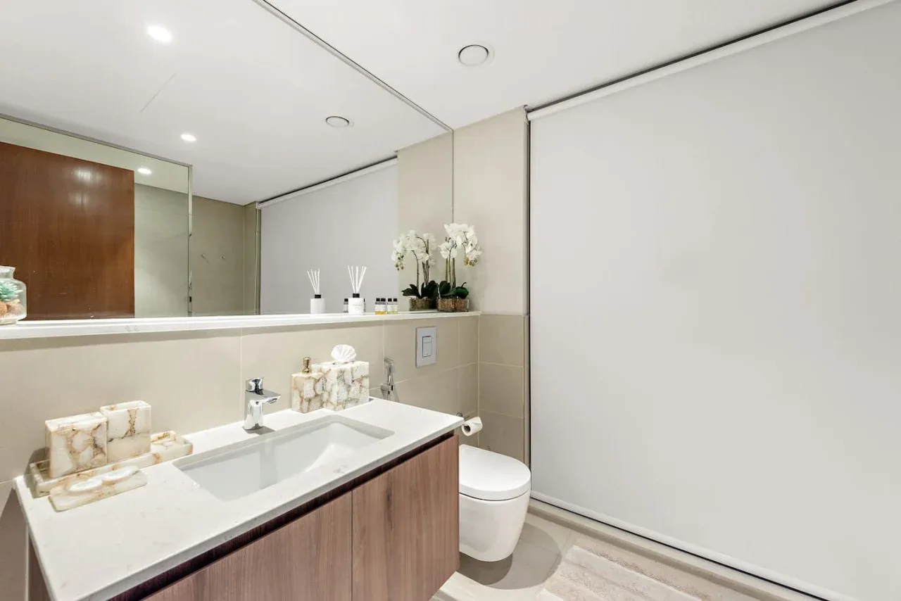 Un baño moderno con un lavabo amplio, espejo e inodoro.