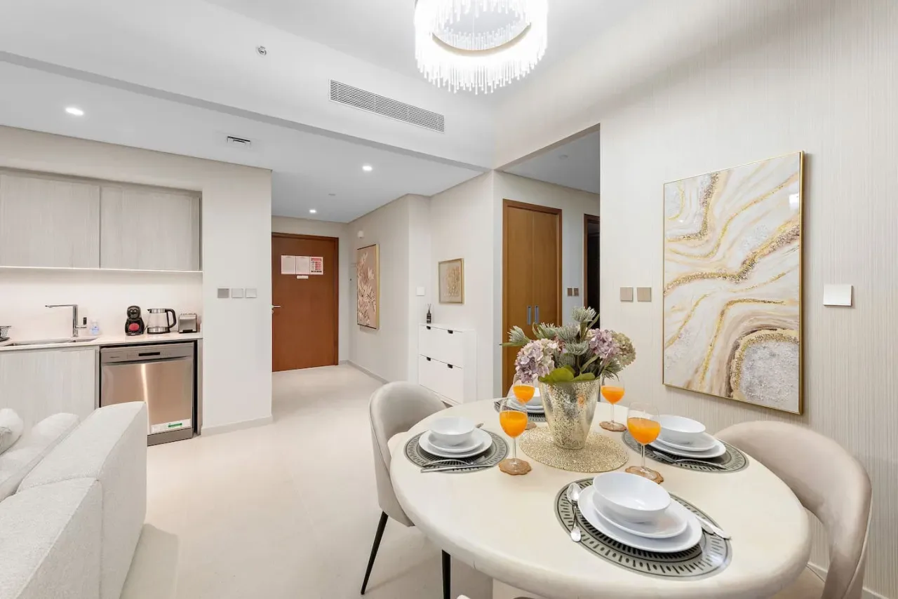 Un comedor luminoso con la mesa puesta junto a una cocina compacta.