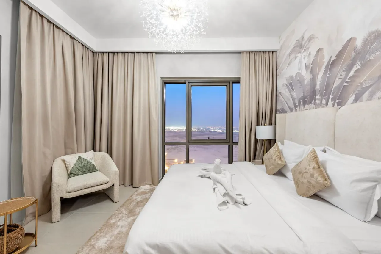 Un dormitorio con una cama grande, una ventana con cortinas y un sillón.