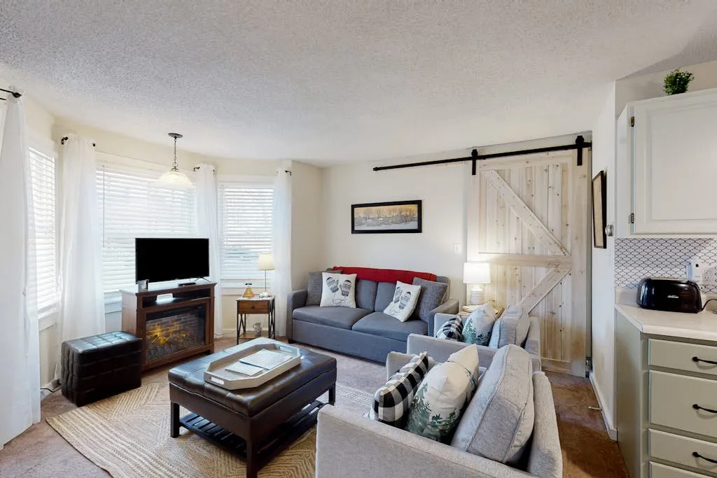 A living room with seating arranged around a coffee table and television.