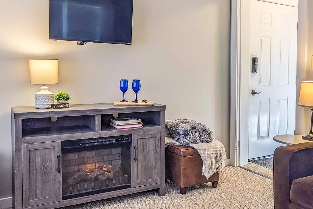 A living room with a media console and an electric fireplace.