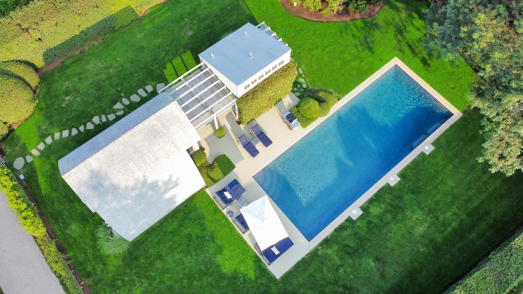 Vista aérea de una piscina rectangular junto a un césped ajardinado.