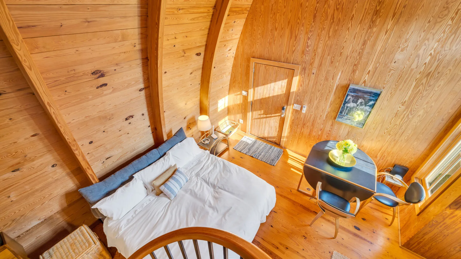 Un dormitorio revestido de madera con una cama y una mesa pequeña junto a la ventana.