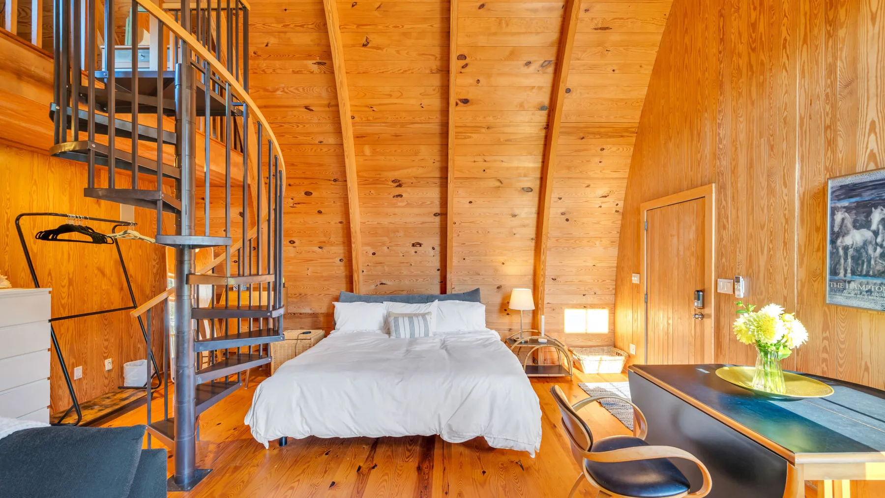 Un dormitorio revestido de madera con una cama y una escalera de caracol.