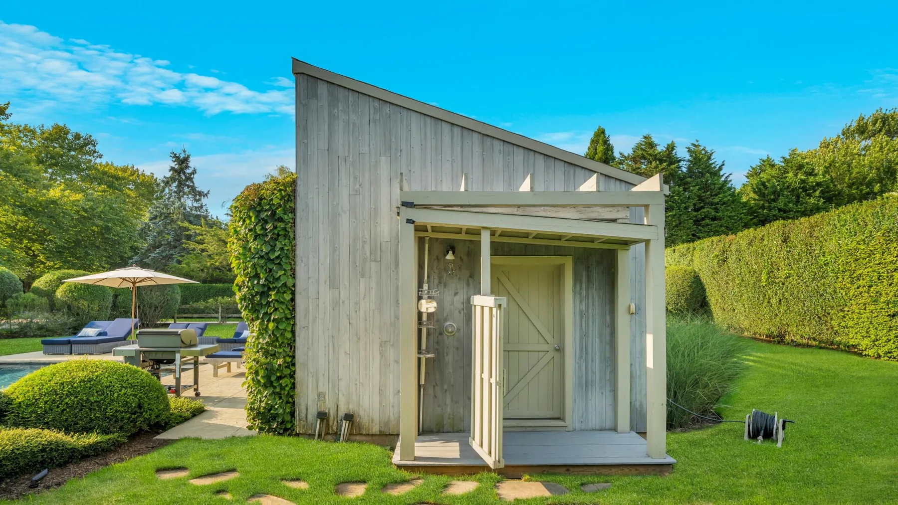 Una entrada de jardín con puerta de madera se abre a un pequeño patio.