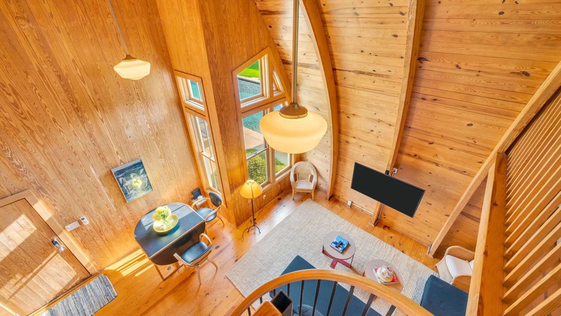 Una sala revestida de madera con ventanas altas y un televisor.
