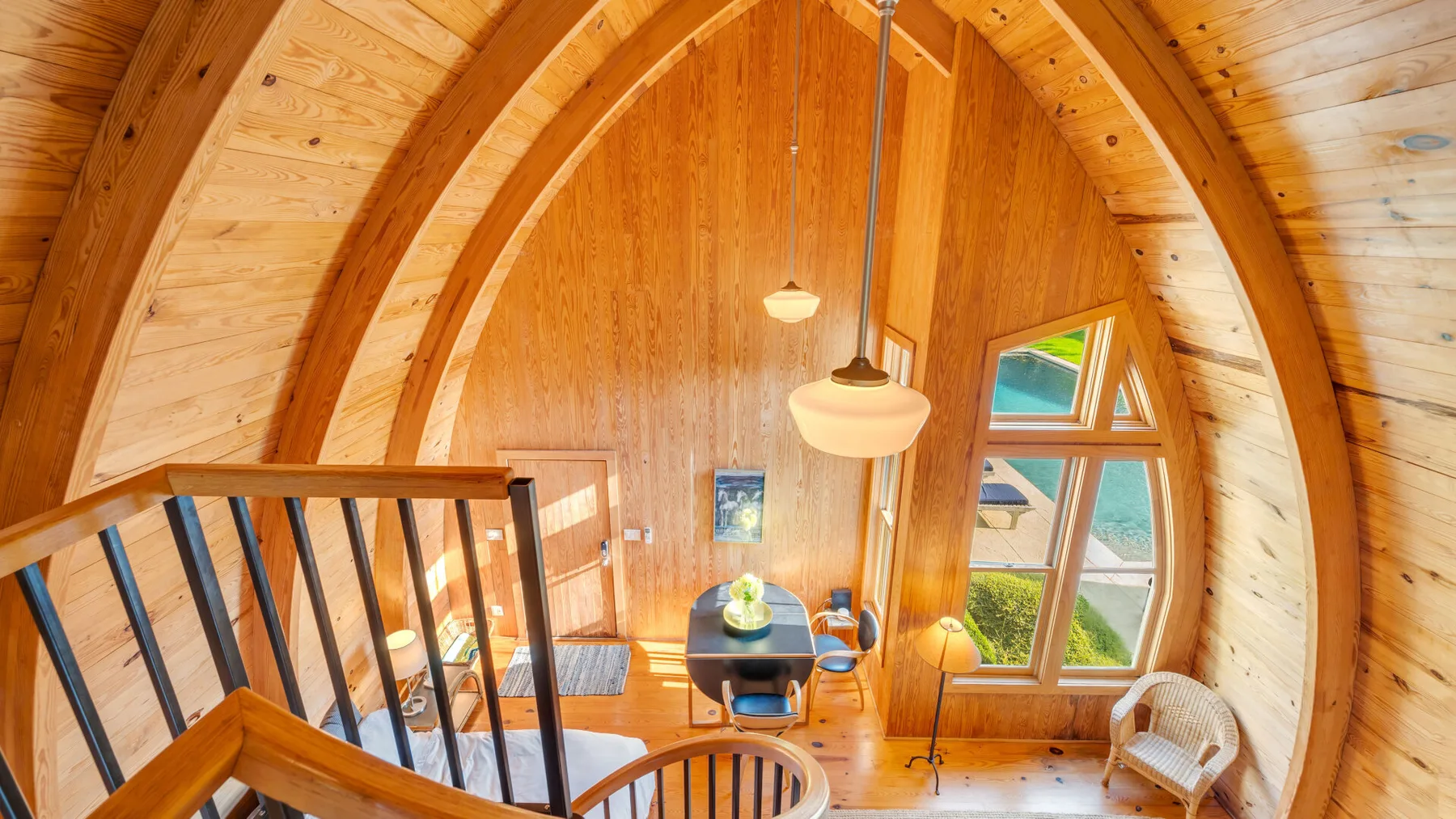 Una habitación de cabaña de madera con paredes curvas, una zona de estar y ventanas grandes.