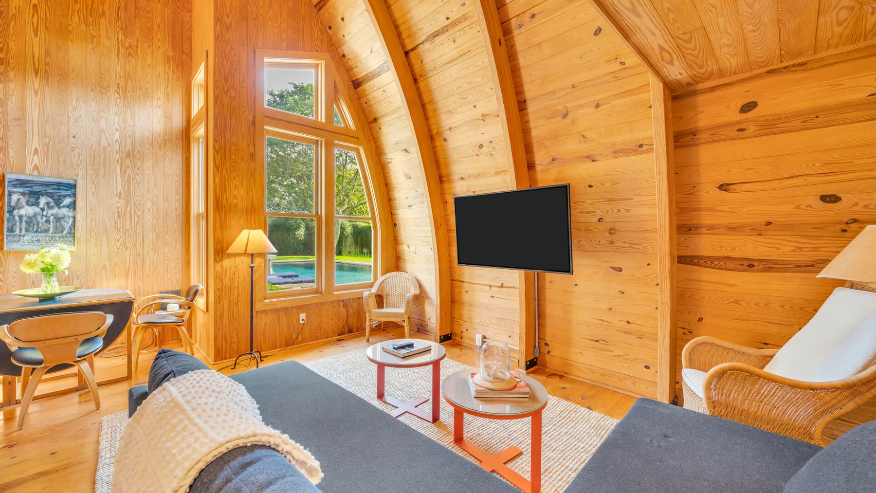 Una sala de estar revestida de madera tiene ventanas grandes y una zona para sentarse.