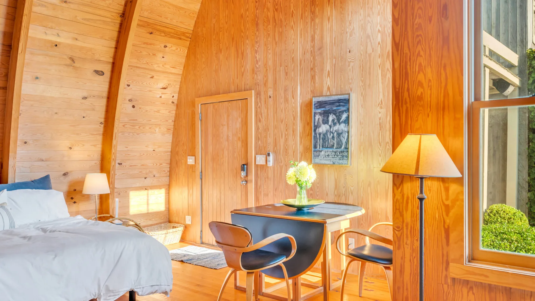 Dormitorio revestido de madera con una cama y una pequeña mesa de comedor.