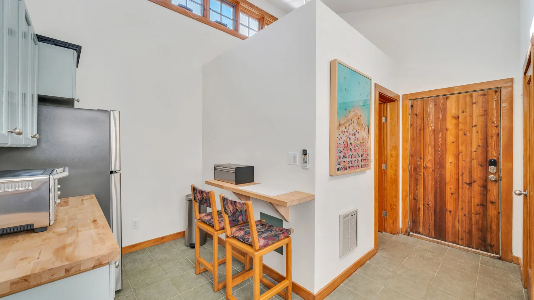 Una cocina luminosa con un rincón de comedor, una barra de madera y taburetes.
