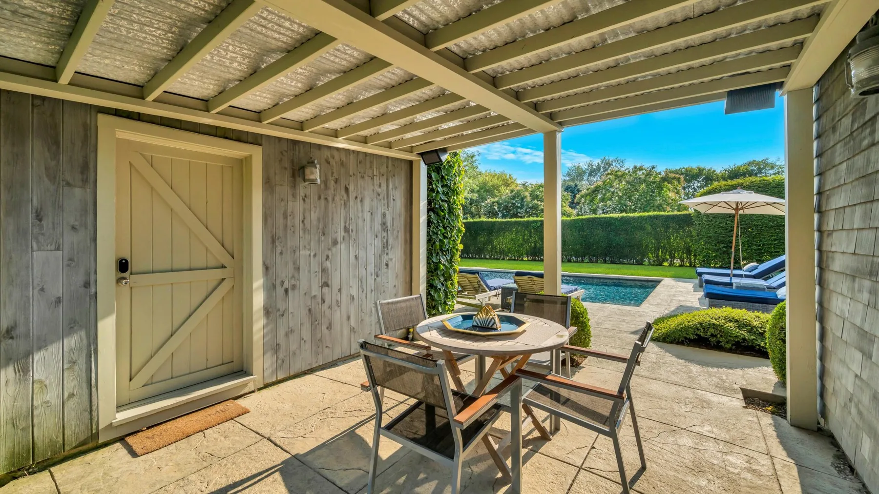 Un patio exterior cubierto con una mesa de comedor frente a una piscina.