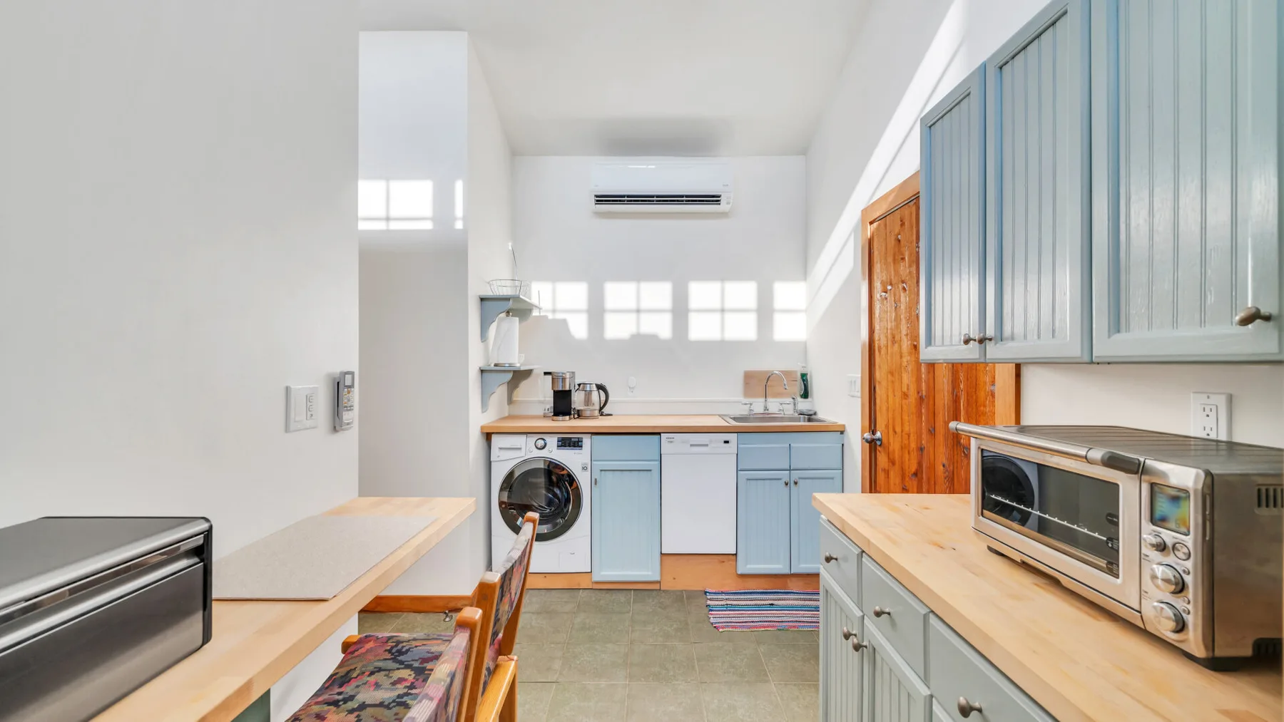 Una cocina luminosa con gabinetes azules, una encimera y un microondas.