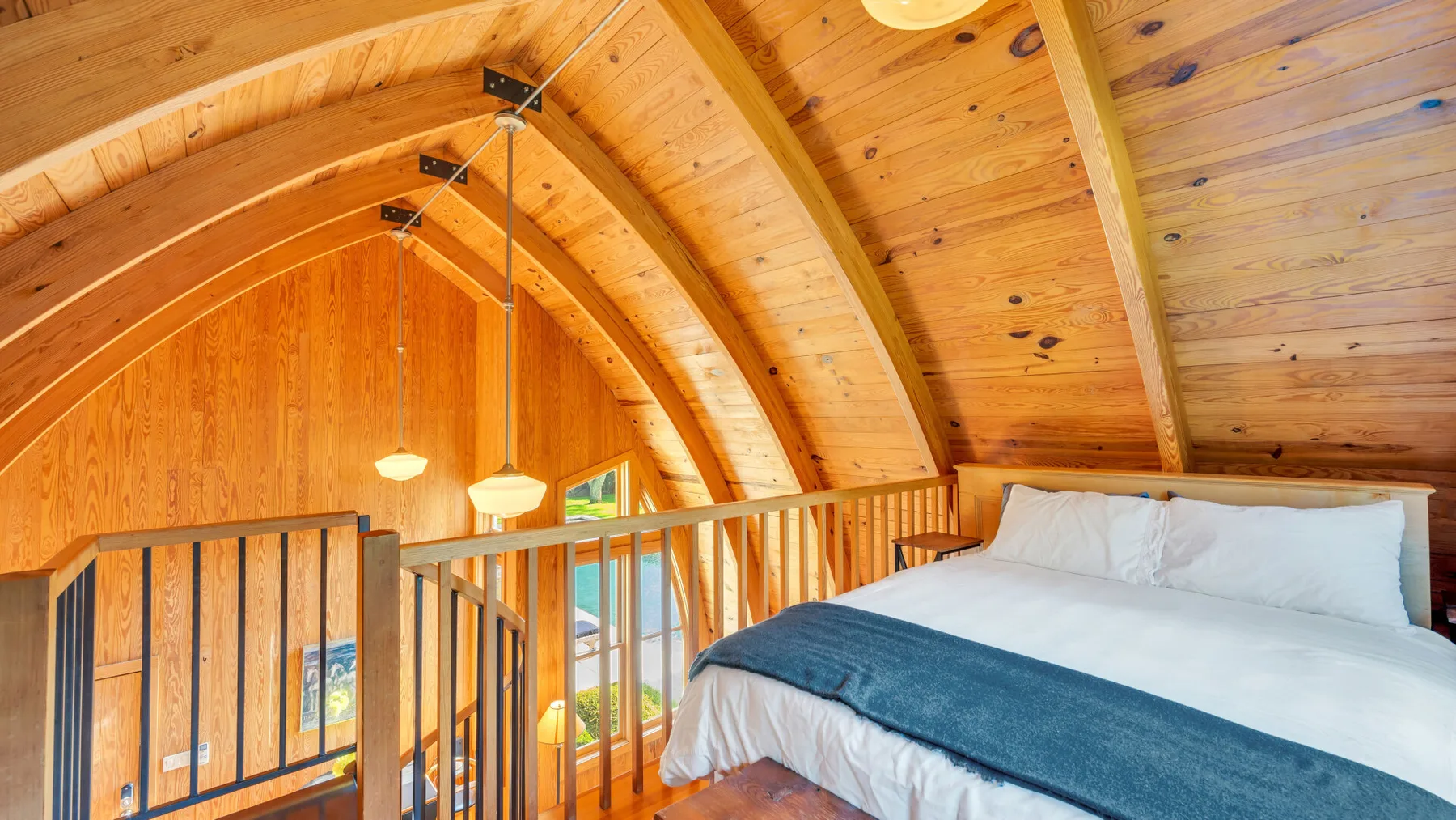 Un dormitorio con una cama bajo un techo de madera inclinado.