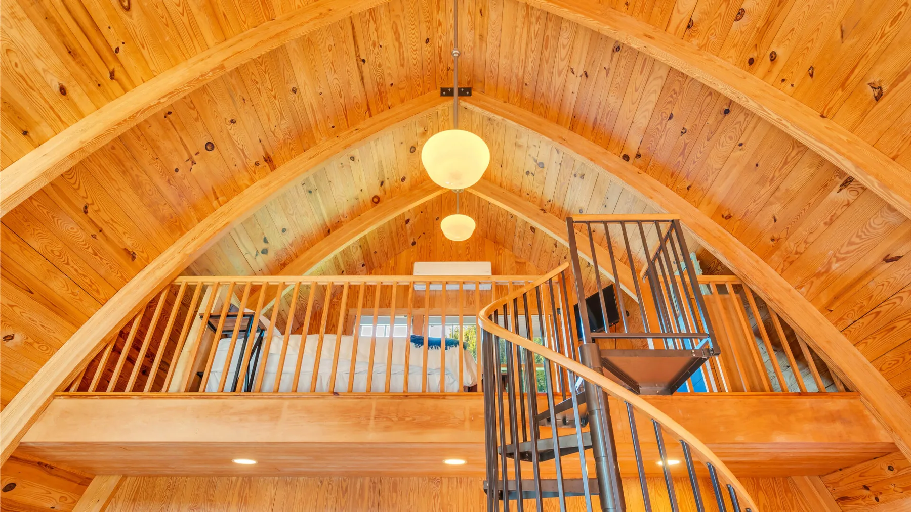 Una habitación revestida de madera con una escalera curva y luces en el techo.