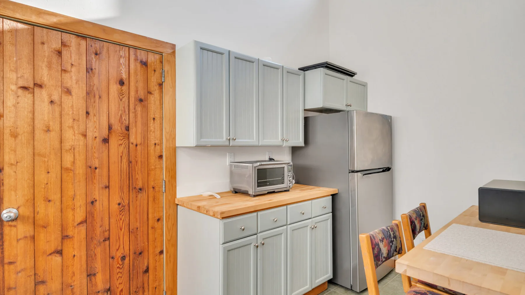 Una cocina compacta con armarios claros, un microondas sobre la encimera y un refrigerador de acero inoxidable.