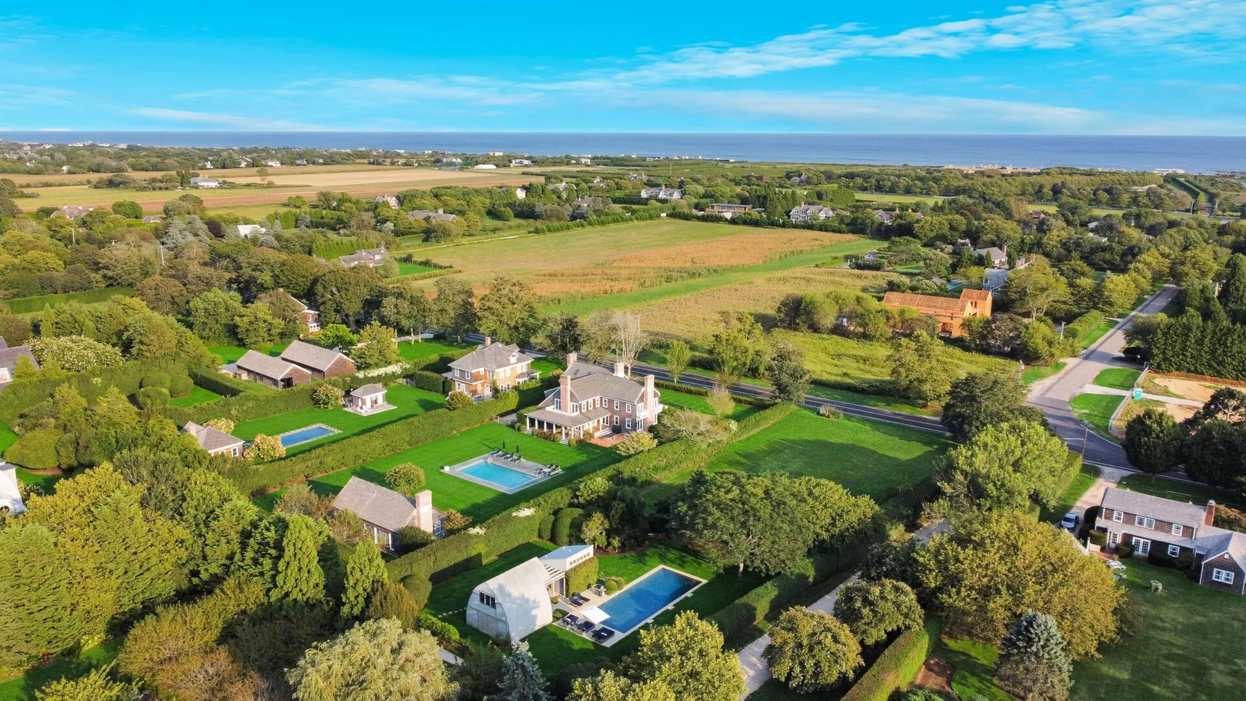 Vista aérea de casas y campos verdes, con varias piscinas.