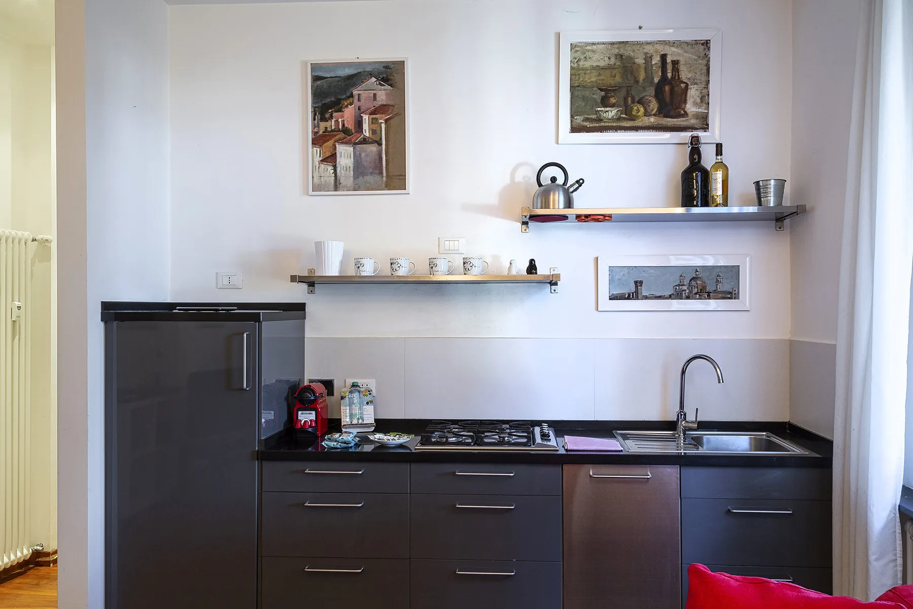A compact kitchen with dark cabinets, a cooktop, and a sink.