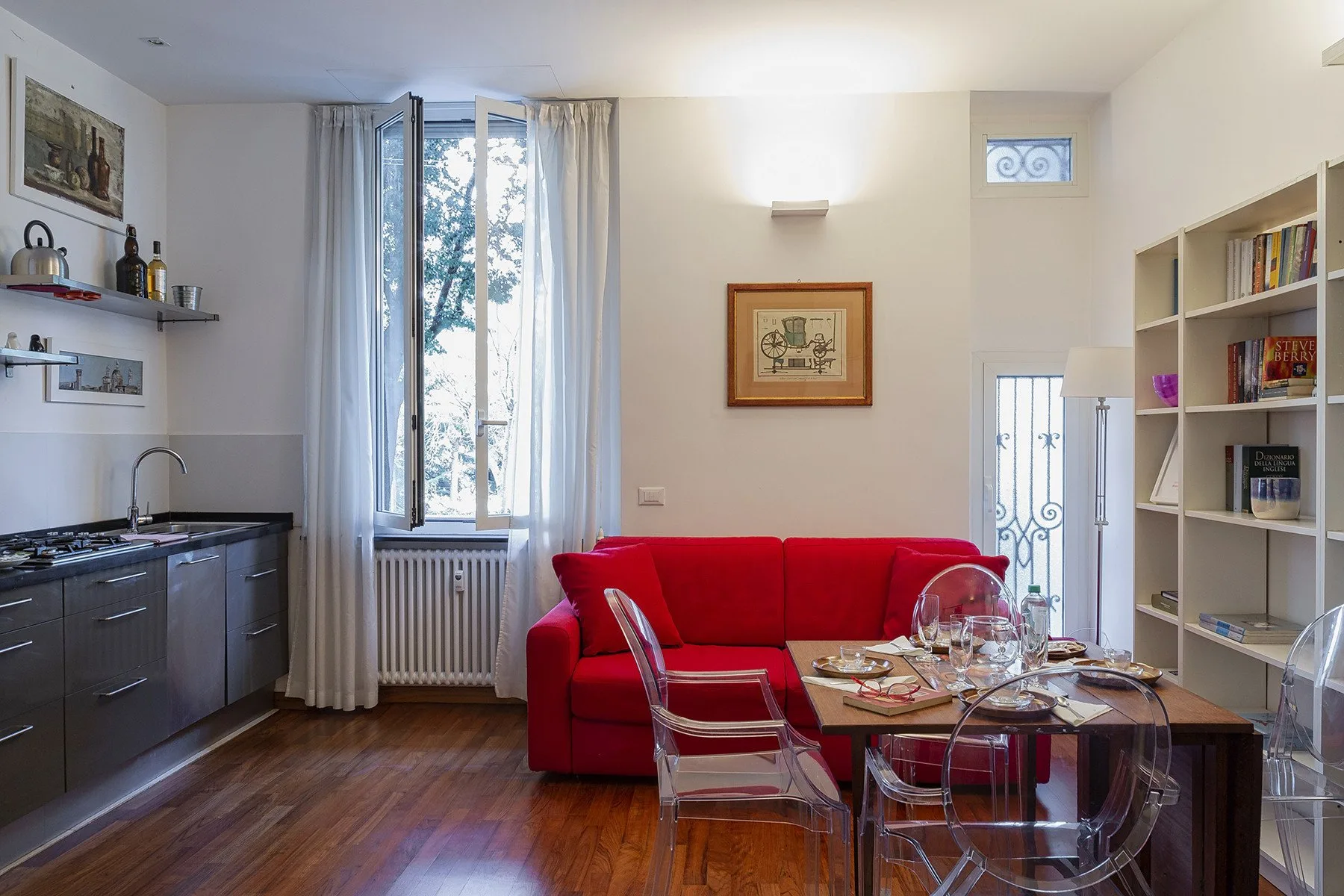 A living room with a red sofa, dining table, and kitchen counter.
