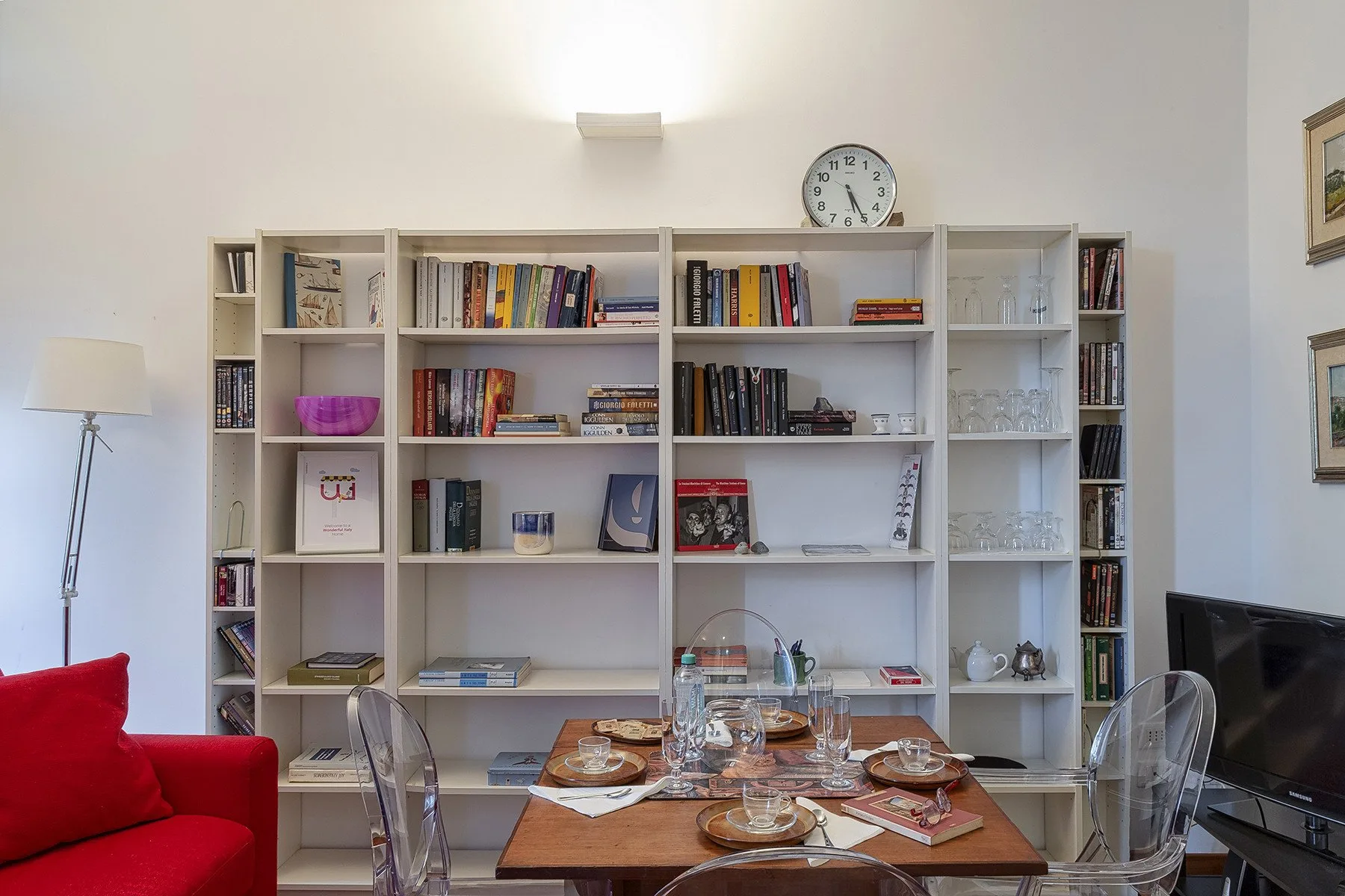 A dining area with a table set in front of a large wall of bookshelves.
