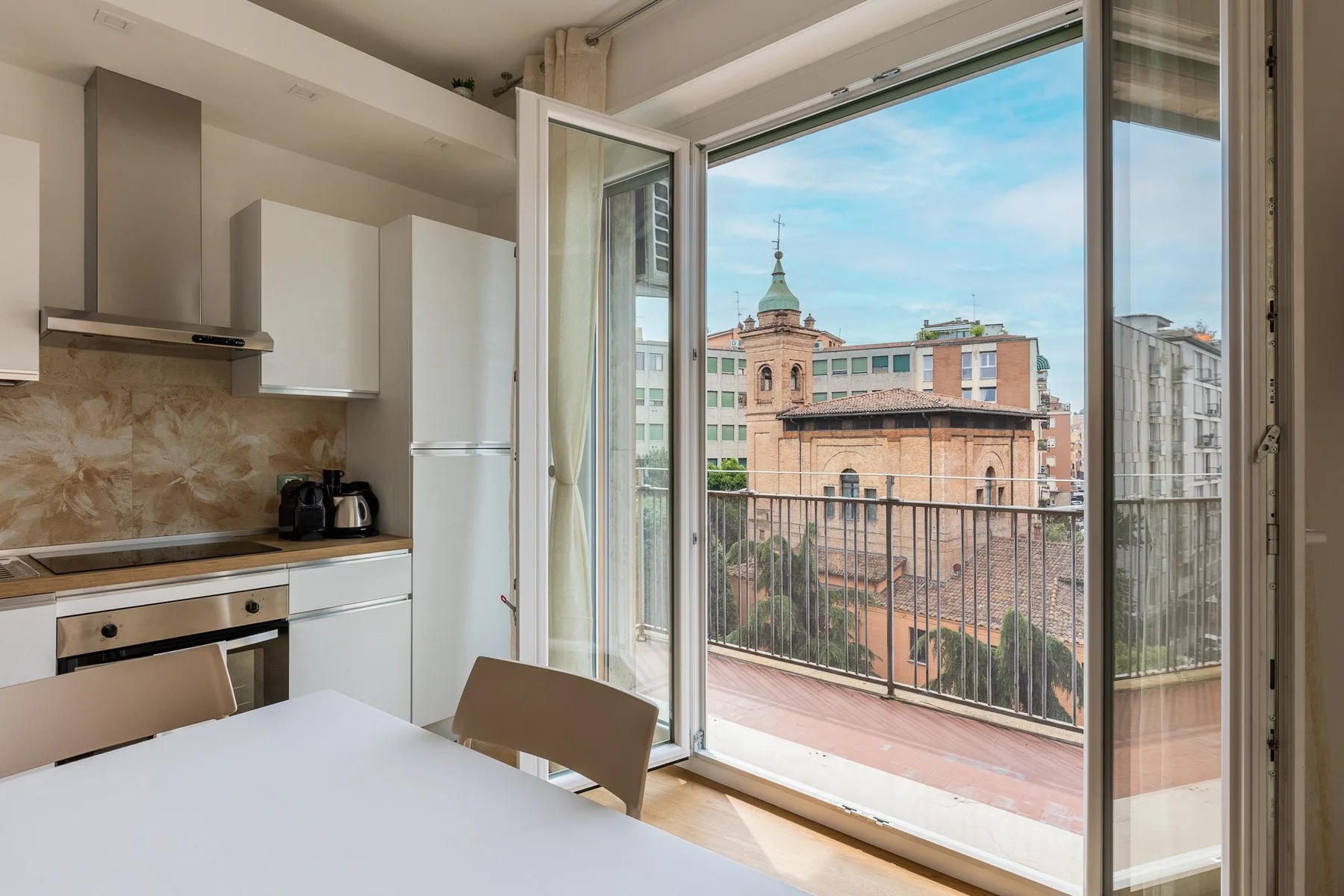 Una cocina da a un balcón con vistas a los edificios cercanos.