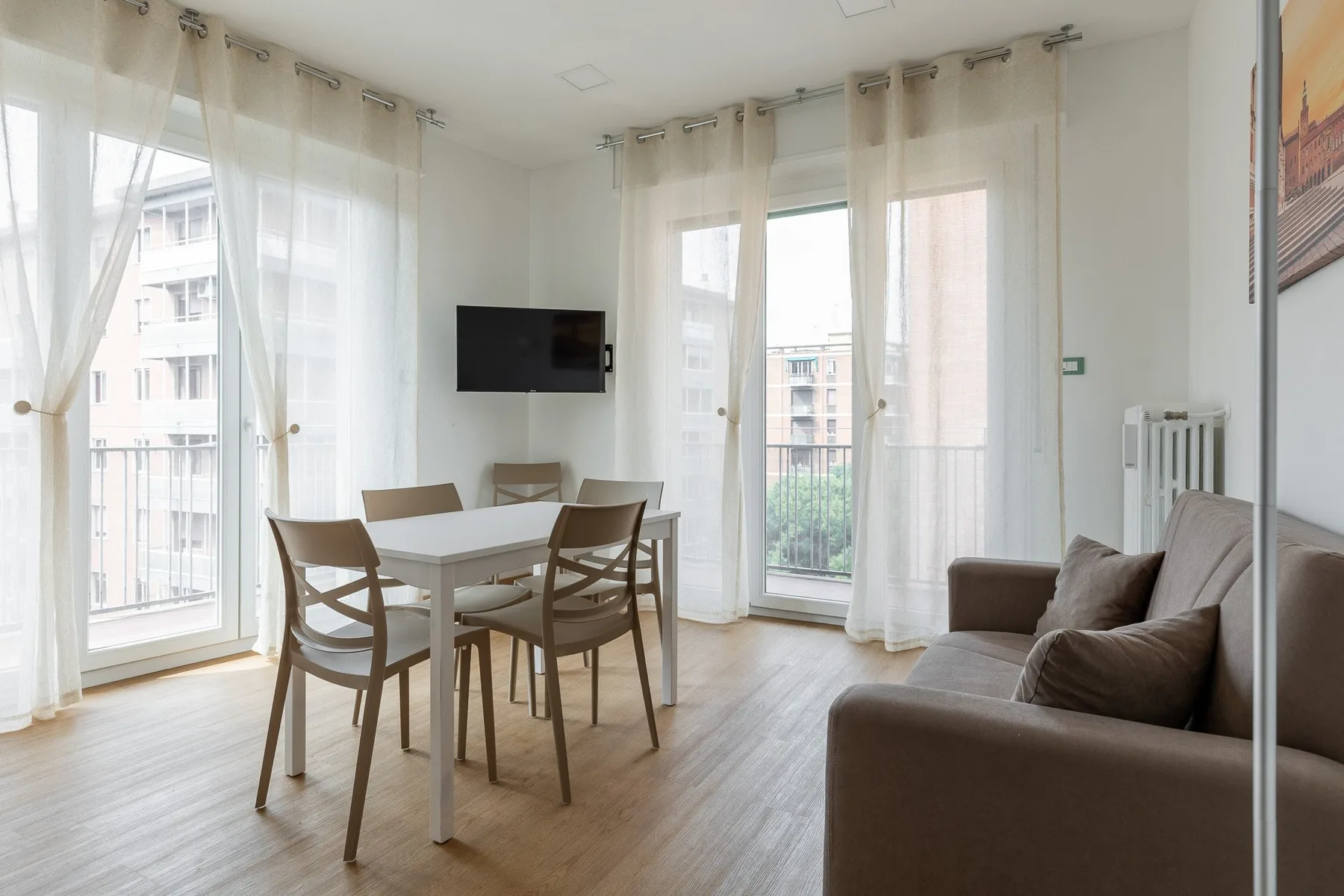 Una luminosa sala-comedor con mesa, asientos y ventanas altas.