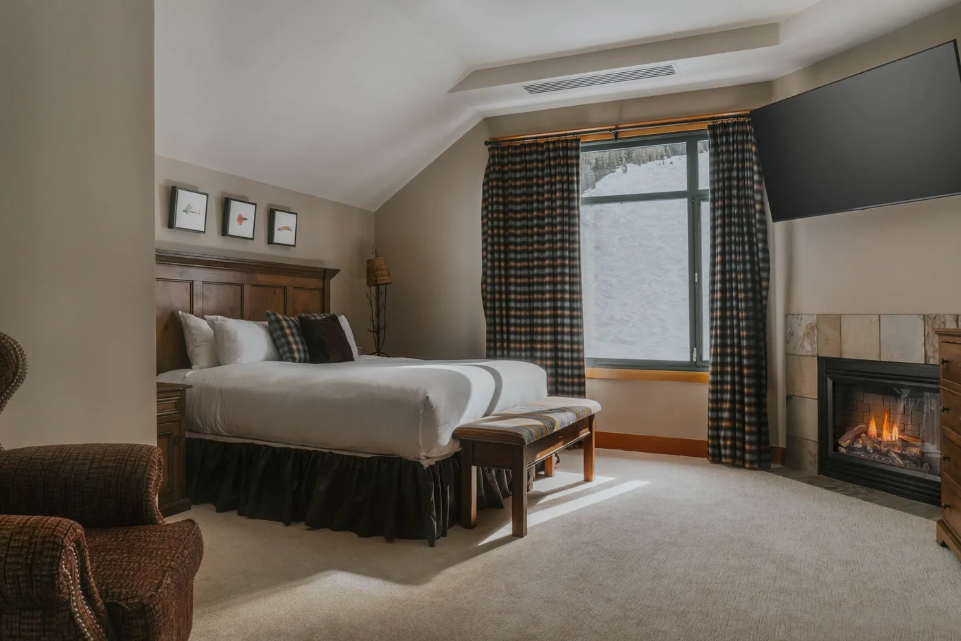 A bedroom with a bed, curtained window, and fireplace.