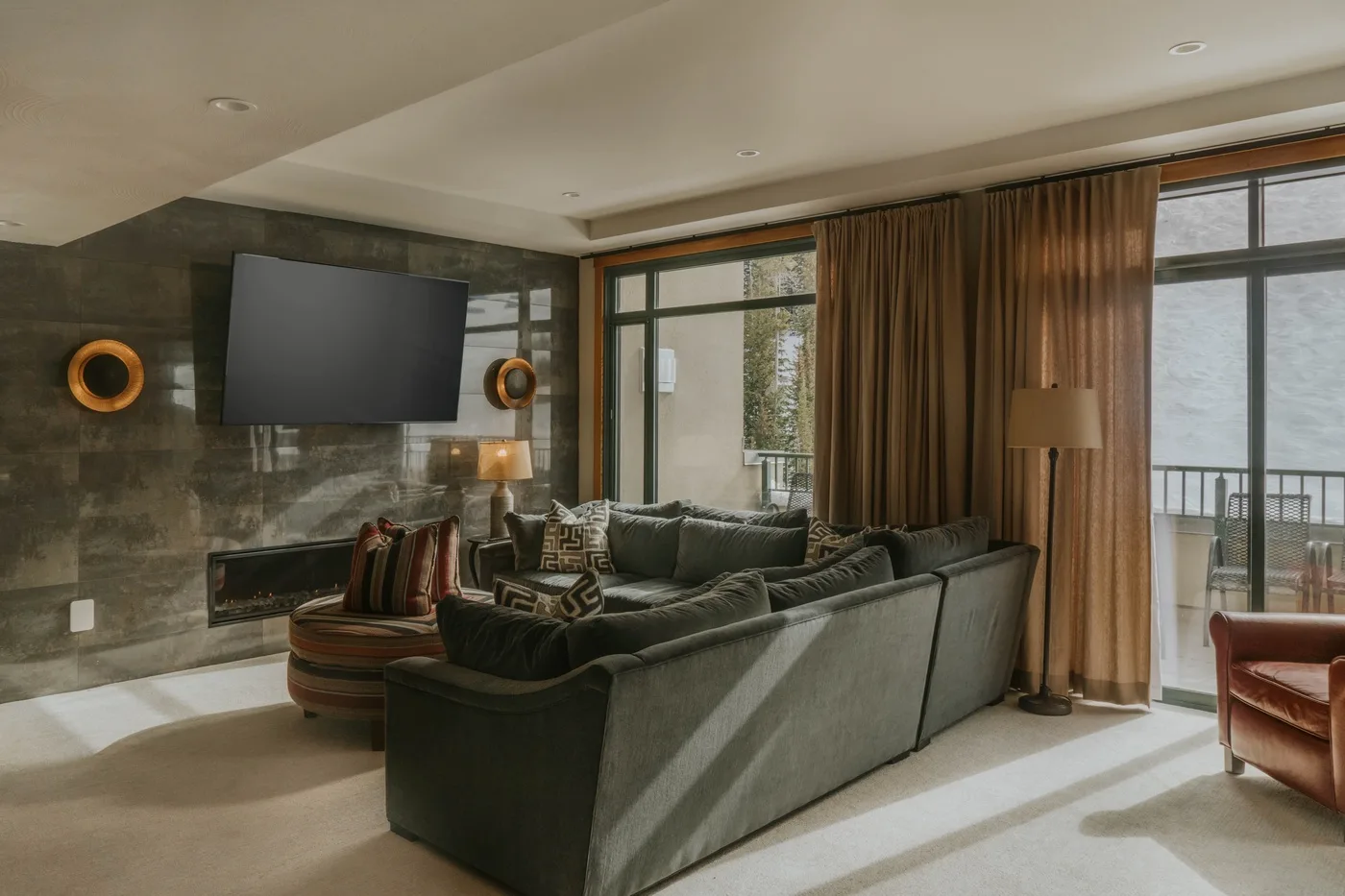 A living room with a large sectional seating area facing a wall-mounted television.