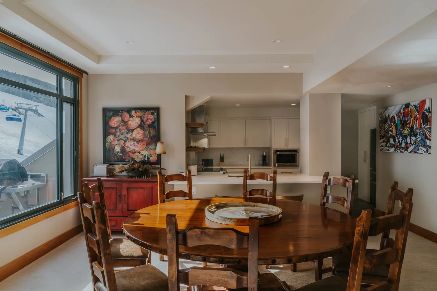 A dining area with a large wooden table beside an open kitchen.