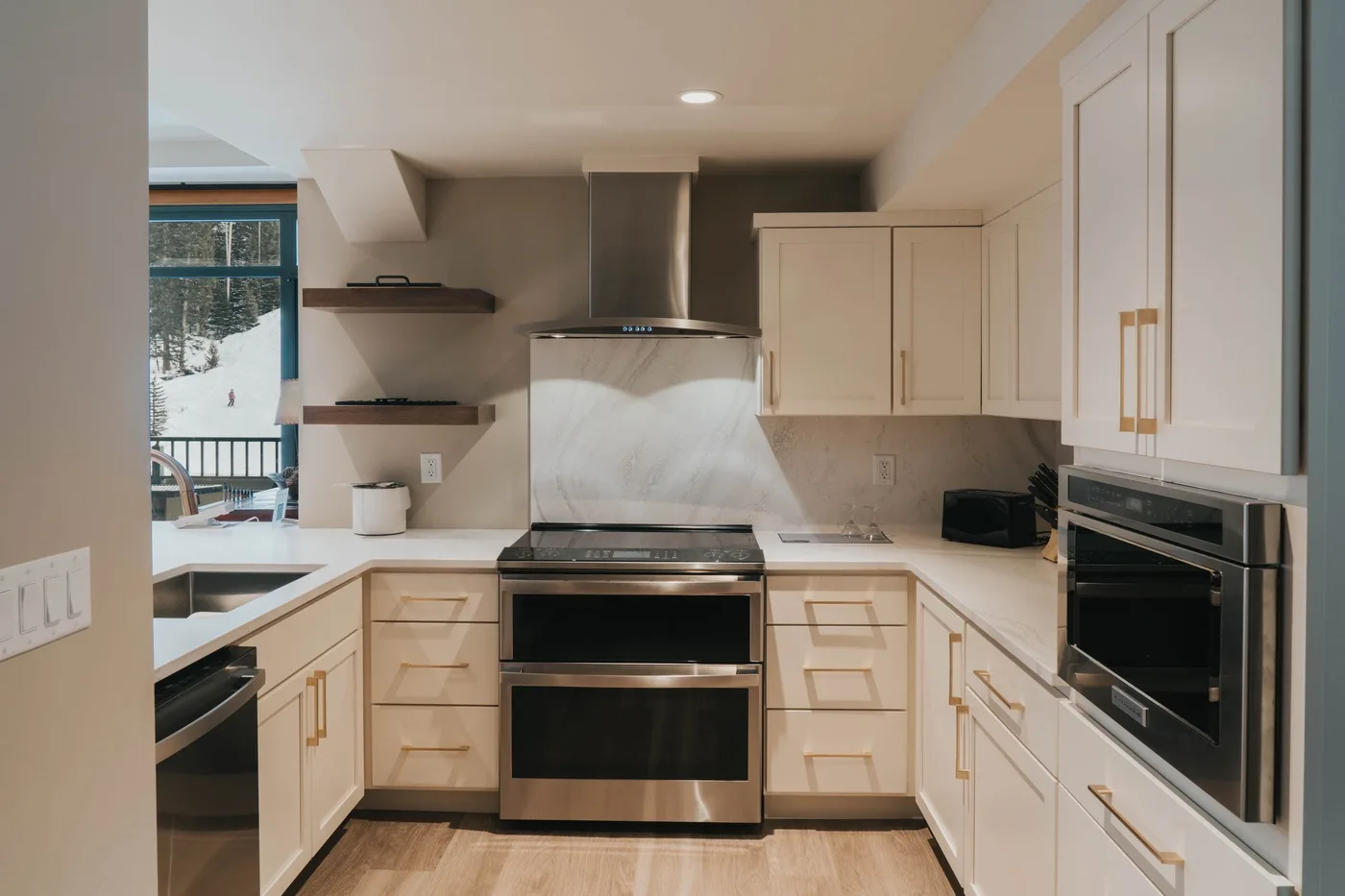 A bright kitchen with light cabinetry, a range, and built-in ovens.