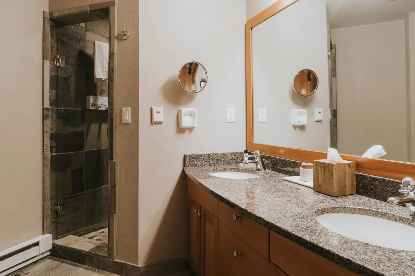 A bathroom vanity with a large mirror sits beside a glass shower.