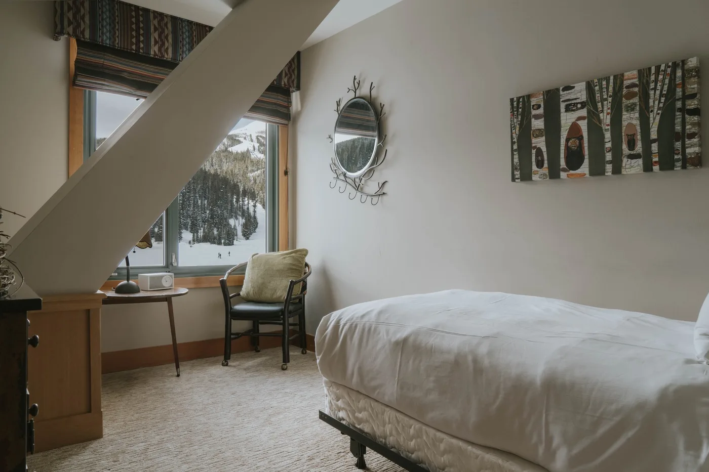 A bedroom with a bed beside a window overlooking a snowy landscape.