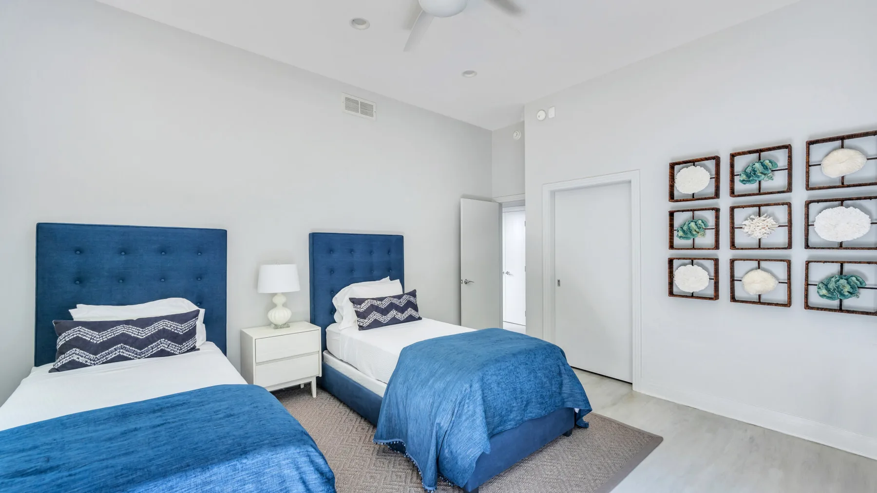 Un dormitorio luminoso con dos camas vestidas con ropa de cama azul y blanca.