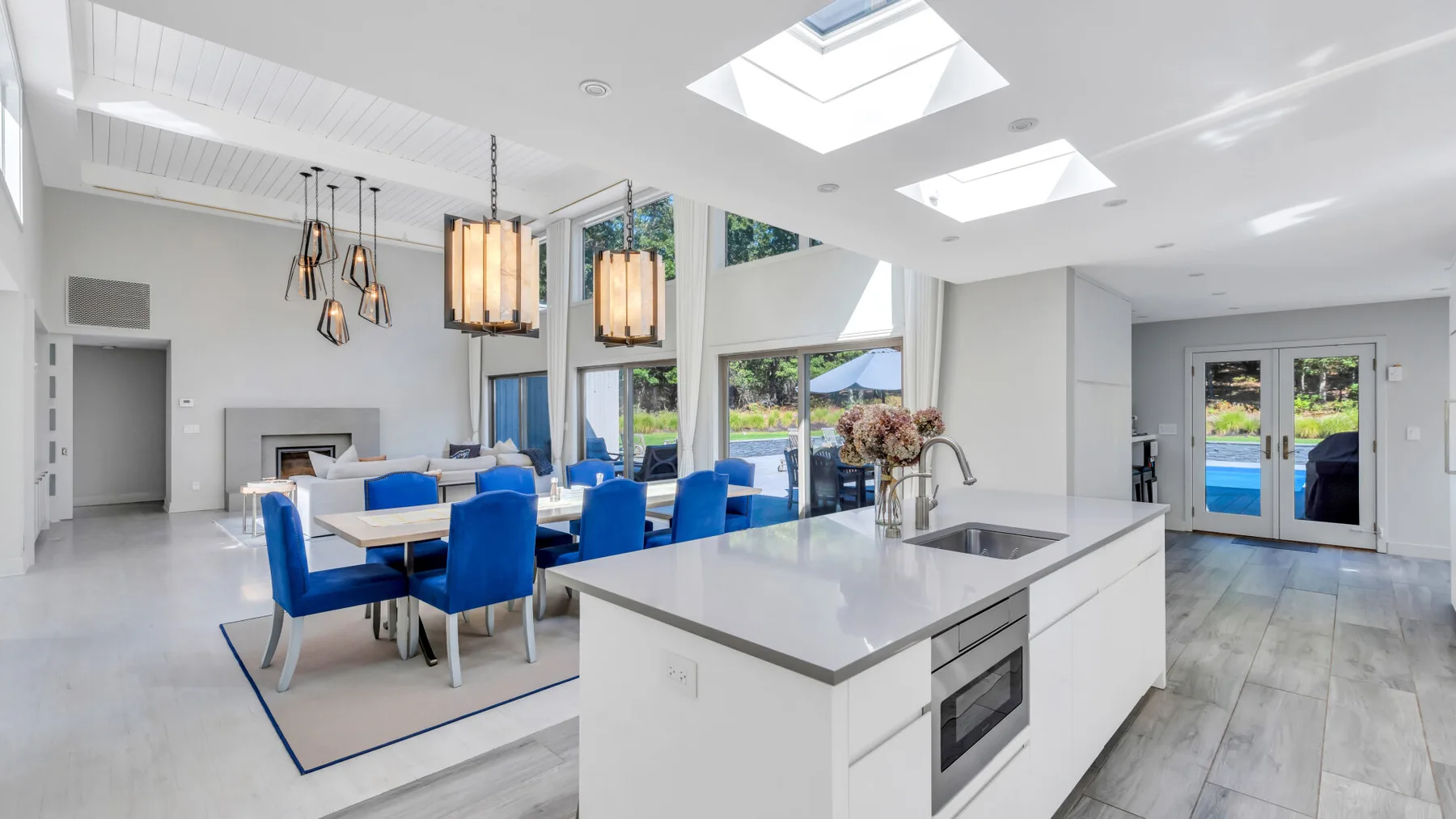 Una luminosa cocina y comedor de planta abierta con una isla central y asientos azules.