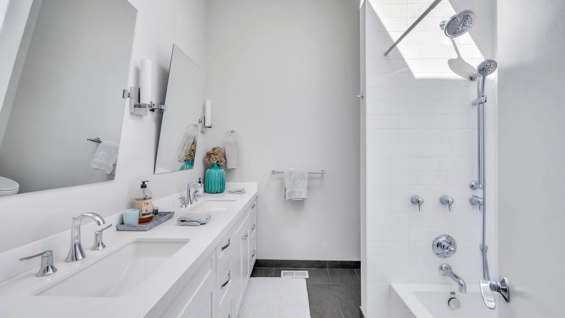 Un baño luminoso con un lavabo largo y una ducha con mampara de vidrio.