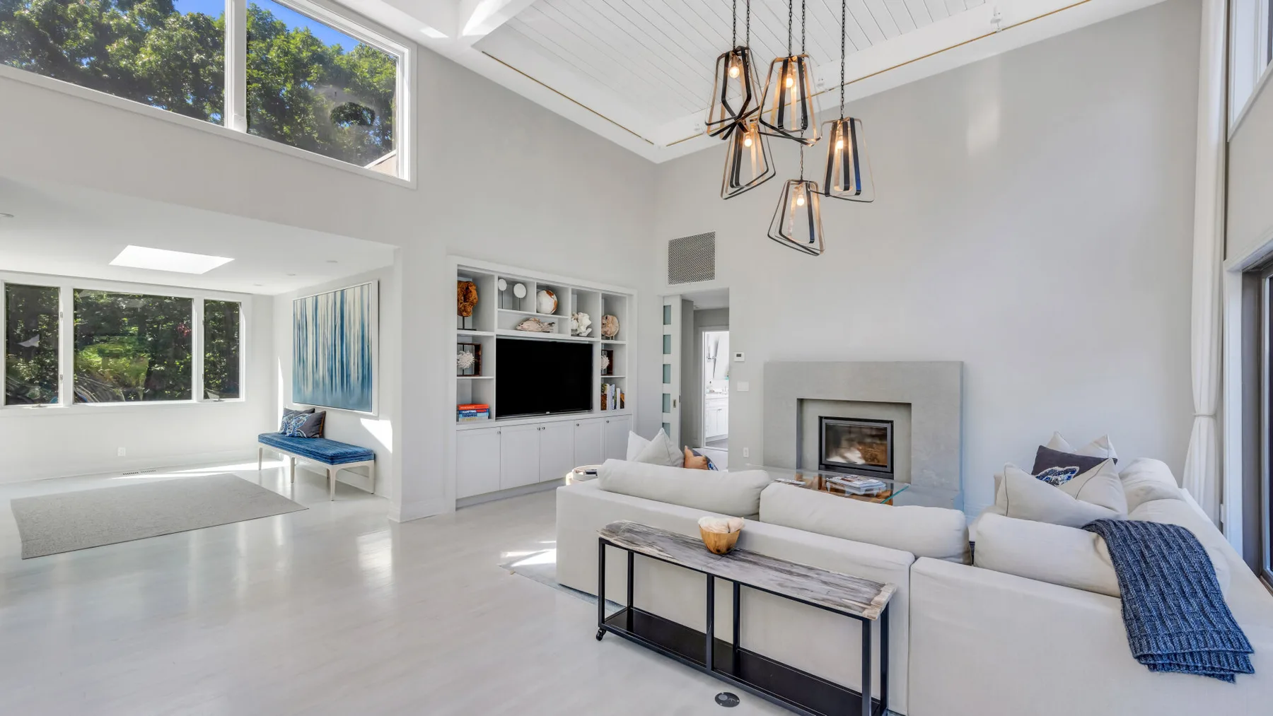 Una sala luminosa con chimenea y grandes ventanas.