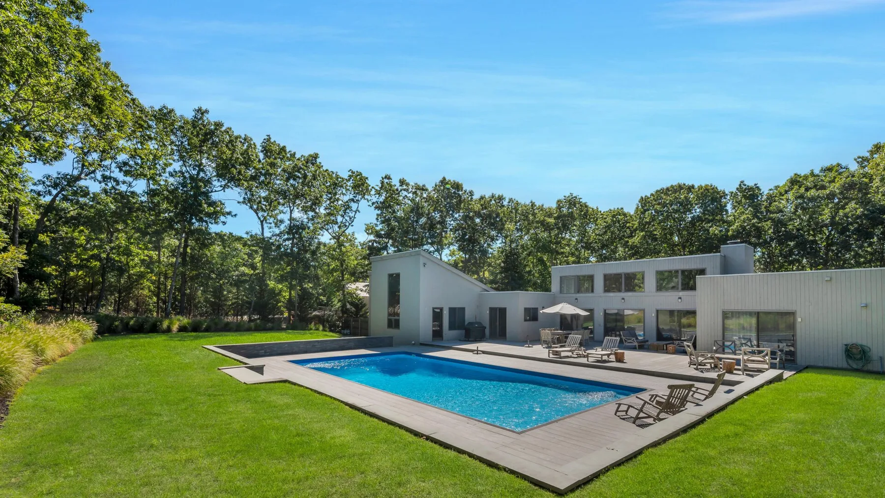 Una casa moderna da a una piscina rodeada de césped.