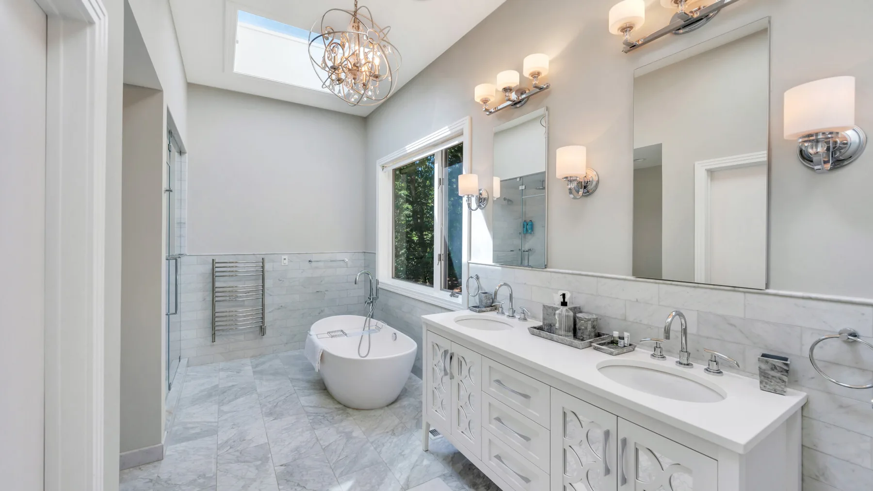 Un baño luminoso tiene un tocador largo, una bañera exenta y un tragaluz.