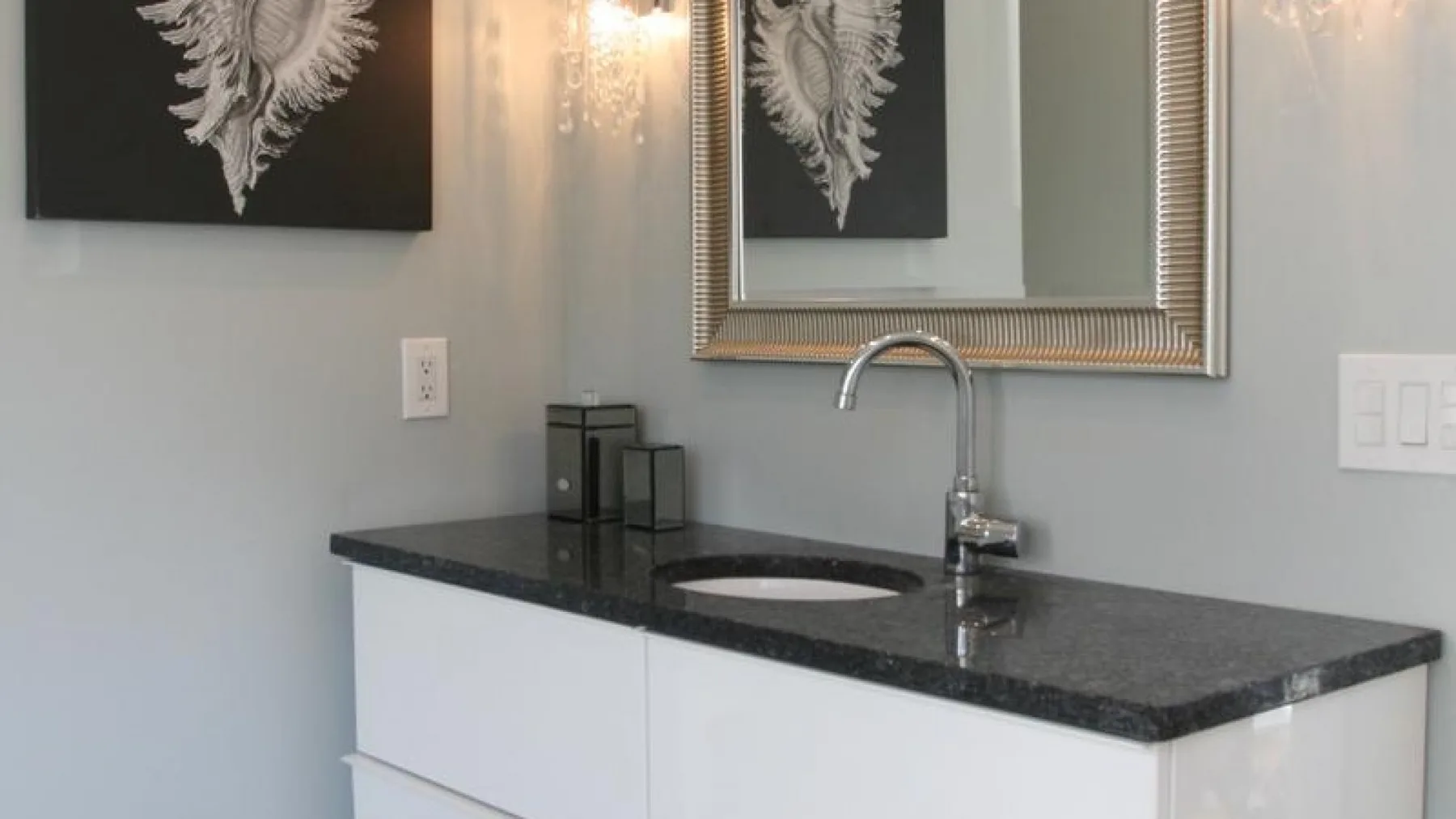 Un tocador de baño con encimera oscura, lavabo y espejo.