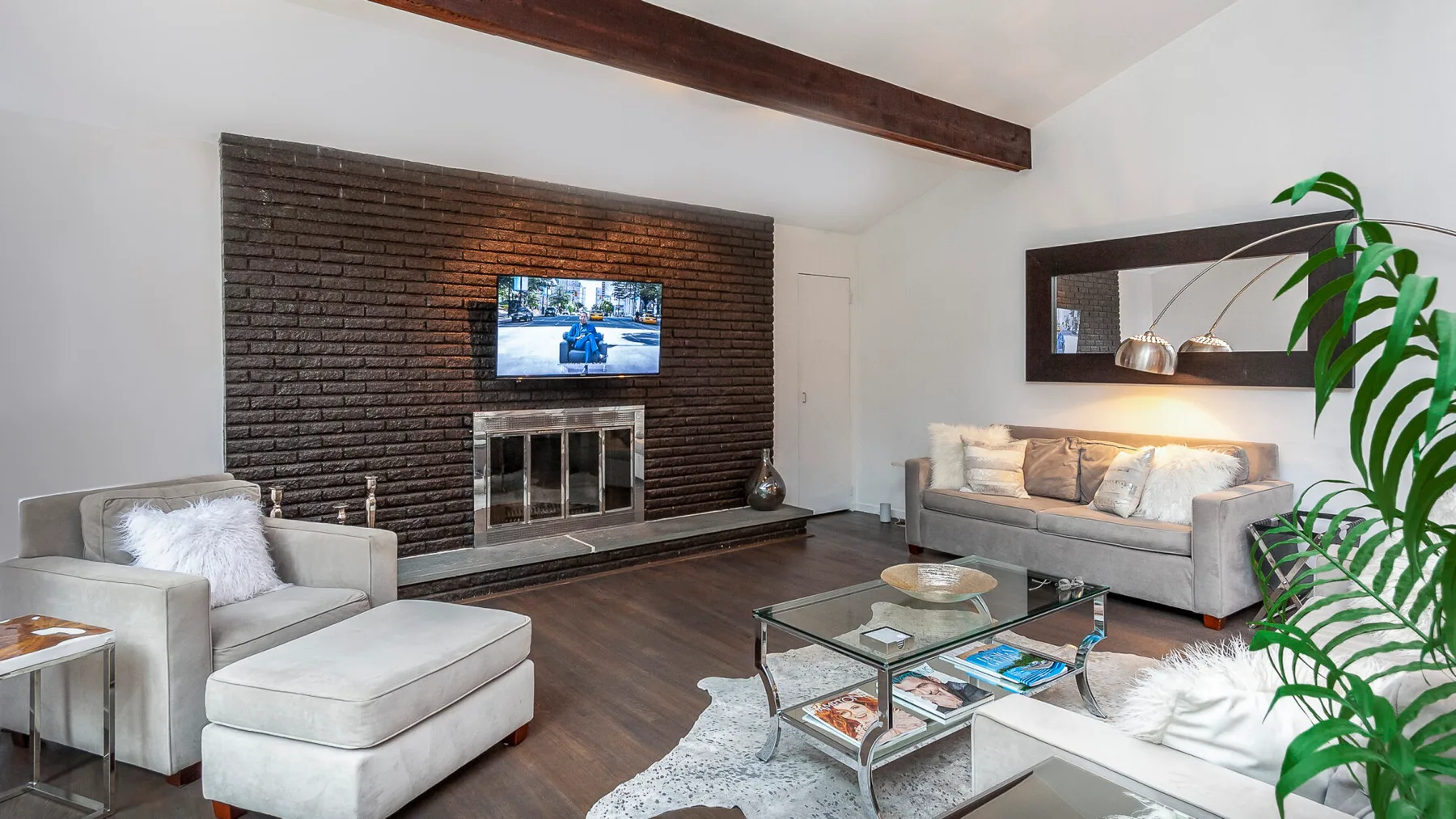 A living room with seating arranged around a glass coffee table and fireplace.