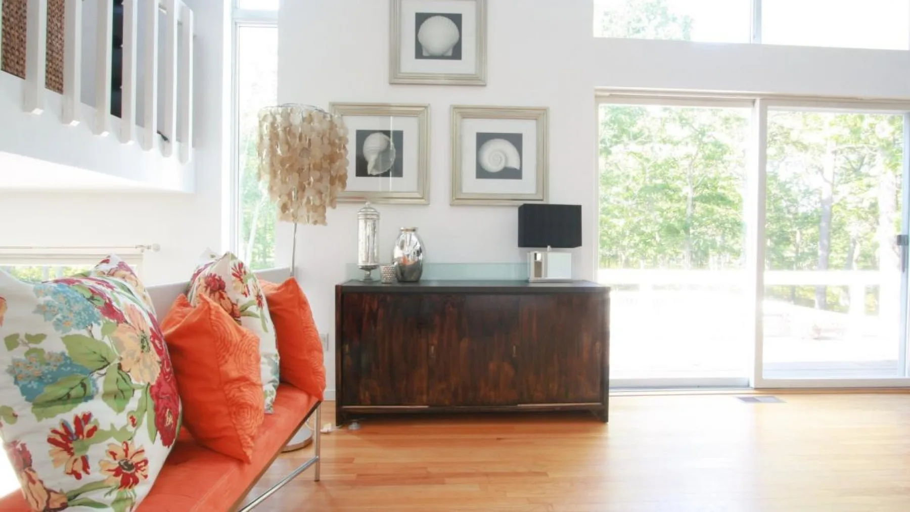 Una sala luminosa con asientos coloridos, un aparador de madera y grandes ventanales.