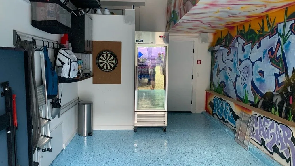 Una colorida sala recreativa interior tiene murales de estilo grafiti y una diana.