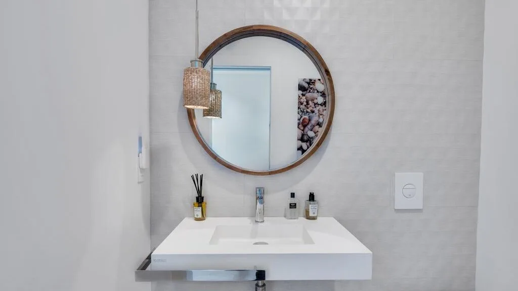 Un lavabo de baño con un espejo redondo en la pared.