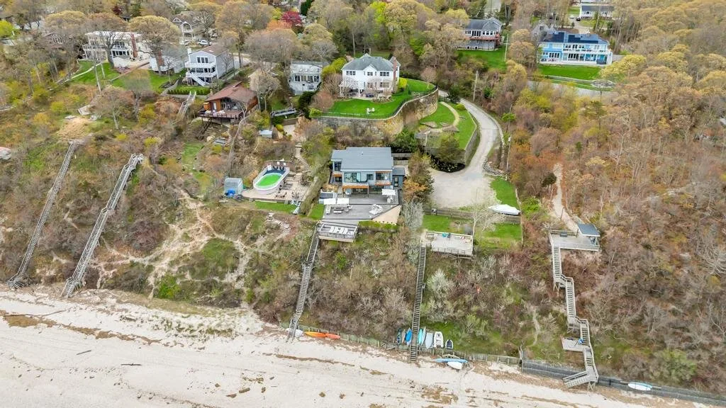 Una vista aérea muestra casas junto a una costa arbolada y una playa de arena.