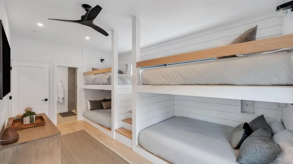Un dormitorio luminoso con literas empotradas y ropa de cama en tonos neutros.