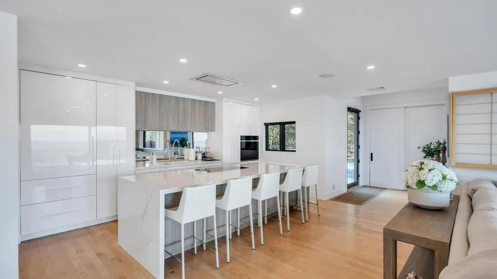 Una cocina y comedor modernos y luminosos se abren a una sala con suelo de madera clara.